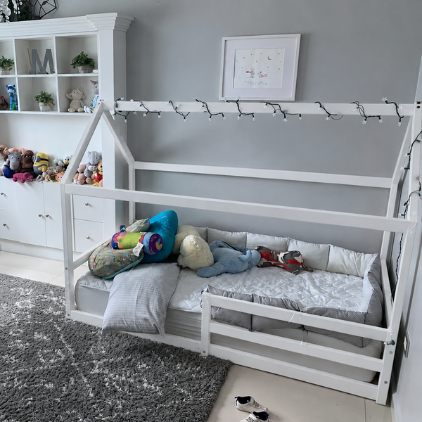 Cama montessori con casita de madera color blanco en habitación