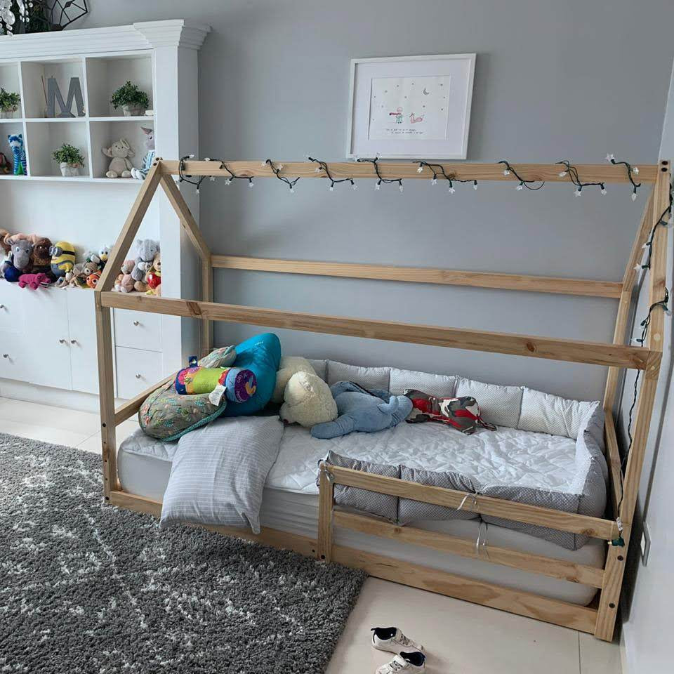 Cama montessori con casita de madera color natural en habitación