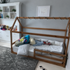 Cama montessori con casita de madera color nuez en habitación
